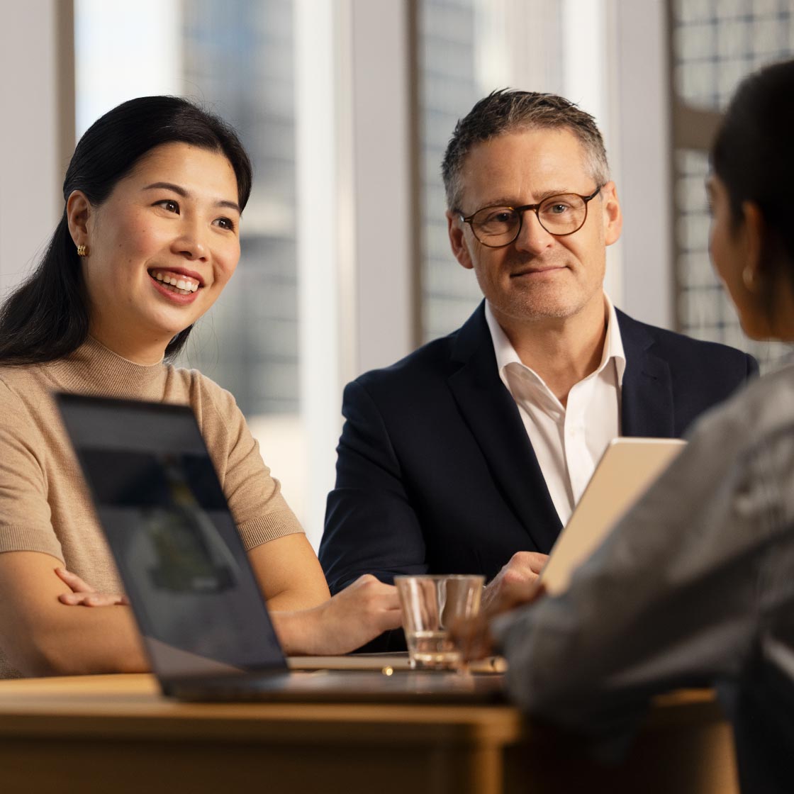 A woman and a man look towards a young woman who is out of focus. They are mid conversation.